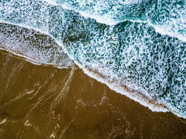 砂浜の海岸に青い海の波のワイドショット