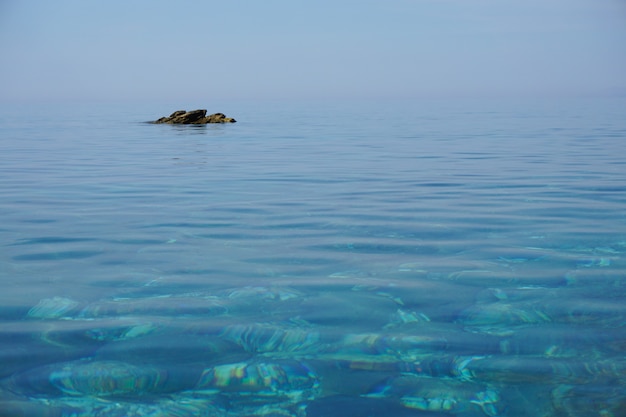 해안에서 멀리 떨어진 암석이있는 잔잔한 바다의 와이드 샷