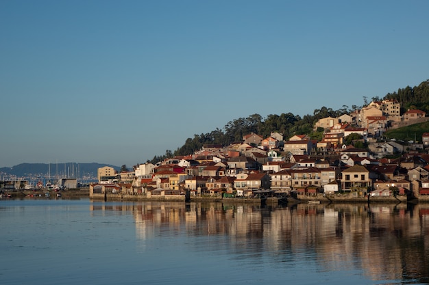 Wide shot of a city full of houses on a hill by the shore on a cool day