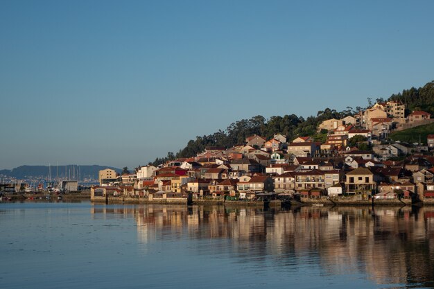 Wide shot of a city full of houses on a hill by the shore on a cool day