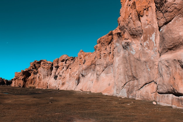 Wide shot of cliffs surrounded by land with a blue sky on a sunny day
