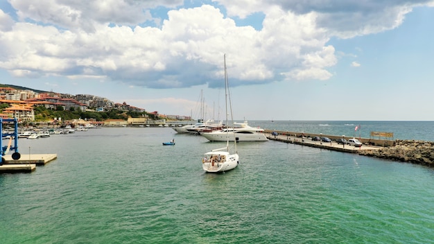 Wide shot of a dock in a coastal city with people sailing in boats near the coast