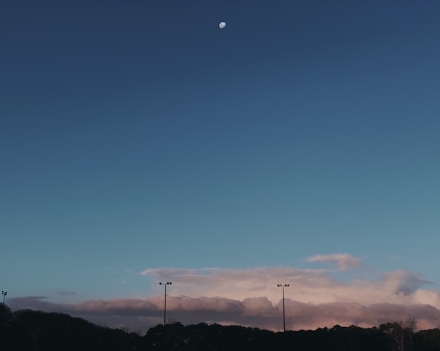 Wide shot of a half moon at the sky over the gray clouds