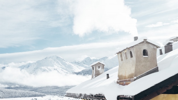 Wide shot of a house near mountains covered in snow