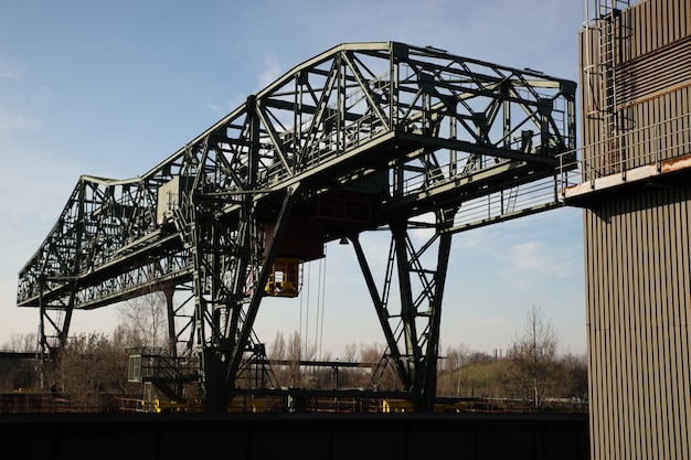 Wide shot of a huge metal structure and a building with a clear blue sky