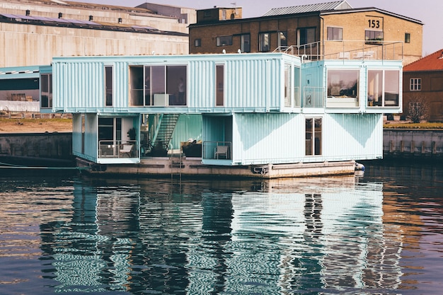 Wide shot of a light blue house on a dock on the body of water