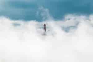Foto gratuita panoramica di un faro coperto di nuvole bianche in un cielo blu