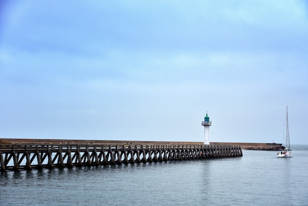 Wide shot of a long pier in the sea under the beautiful blue sky