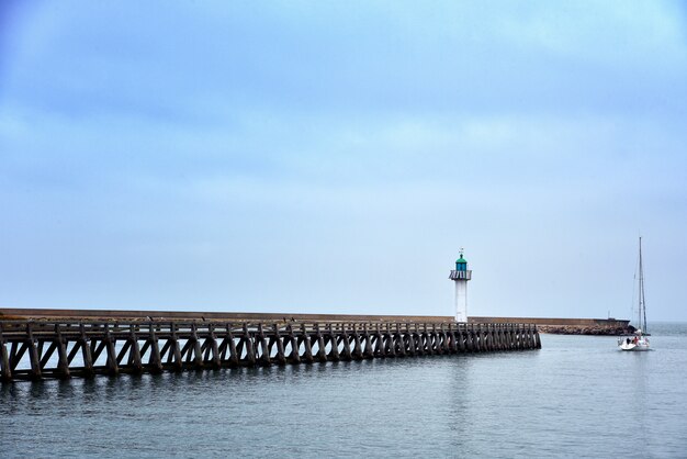 Wide shot of a long pier in the sea under the beautiful blue sky