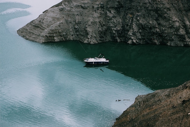 Wide shot of a motorboat on the body of water in the middle of mountains