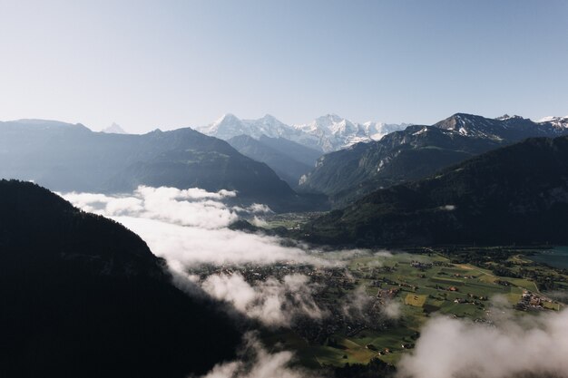 Wide shot of mountains and hills surrounded with green meadows and fog