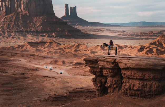 Free photo wide shot of a person on a horse near red cliffs under a blue sky