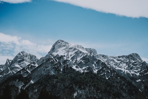 Wide shot of rocky mountains covered in snow and the beautiful blue sky in the background