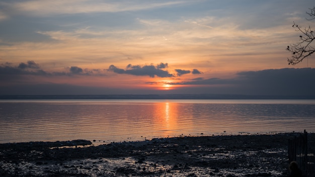 Wide shot of a sea under a sky with clouds during sunset