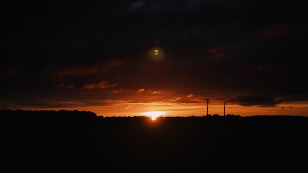 Wide shot of the silhouettes of hills in the countryside at sunset