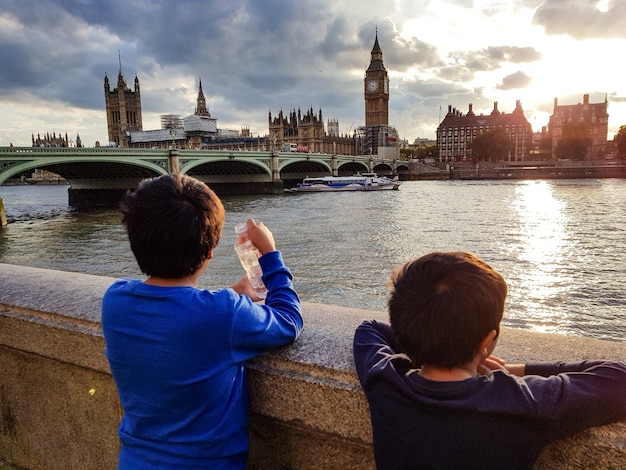 Foto gratuita panoramica di due giovani ragazzi che godono della vista della bella architettura da un ponte