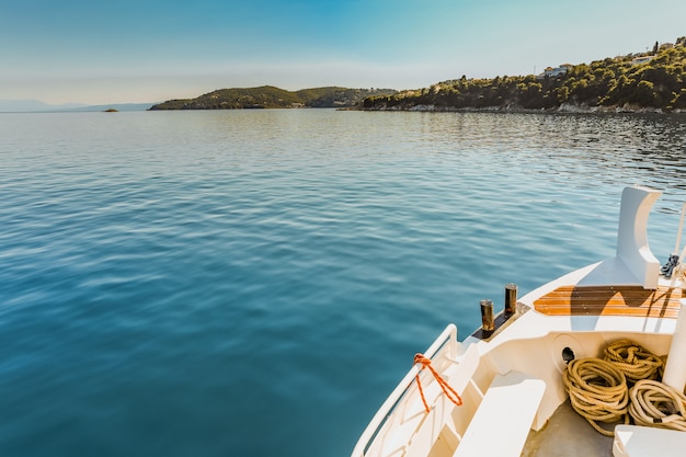 Foto gratuita panoramica di una canoa bianca sul corpo d'acqua vicino ad un'isola verde sotto un chiaro cielo blu