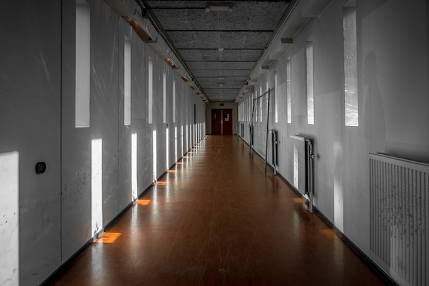 Wide shot of a white hallway with reflections of light from windows