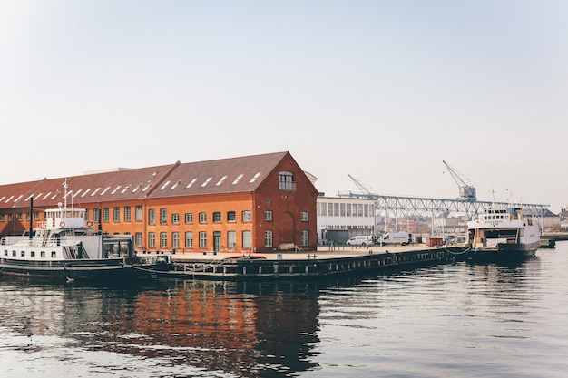 Wide shot of white yachts on the body of water near a port with orange houses