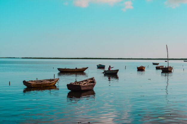 Wide shot of wooden small boats in the water with an African-American person in one of them