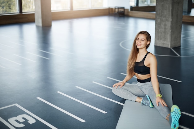 Wide shot of young beautiful fitness trainer stretching before a hard pilates training session. Perfect healthy body concept.