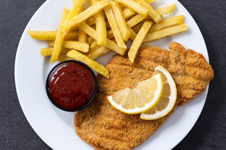 Free Photo wiener schnitzel with fried potatoes on black background