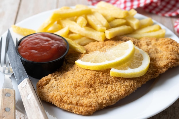 Wiener schnitzel with fried potatoes on wooden table