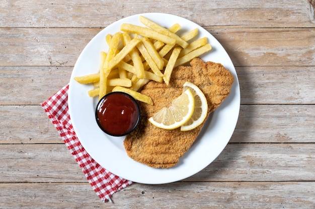 Free photo wiener schnitzel with fried potatoes on wooedn table