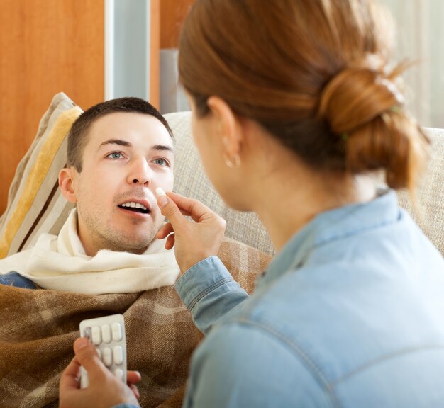 Wife giving pills to husband