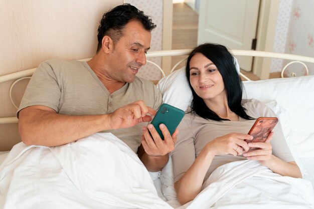 아내와 남편이 침대에서 휴대폰을 확인하고 있다