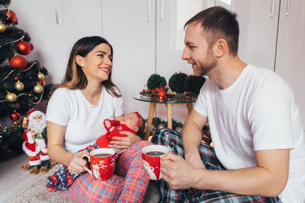 Жена и муж держат чашки кофе и сидят на полу