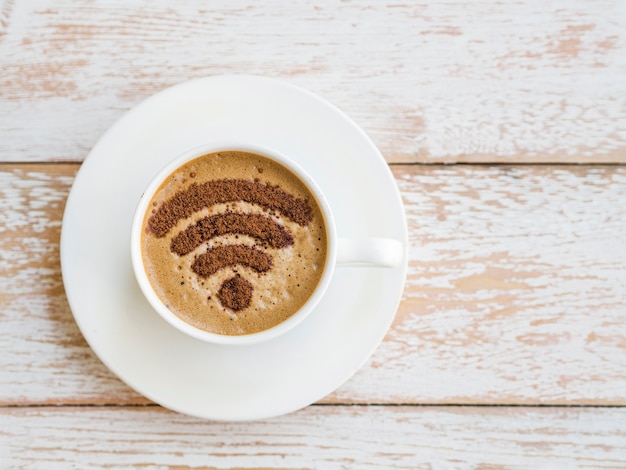 Wifi symbol drawn on cup on wooden background