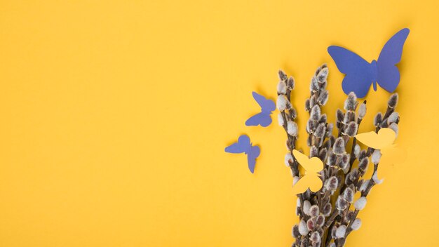 Willow branches with paper butterflies on yellow table