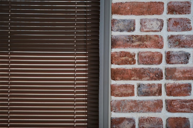 Window with brown blinds and a brick wall made of old bricks loft interior industrial interior as a background closeup