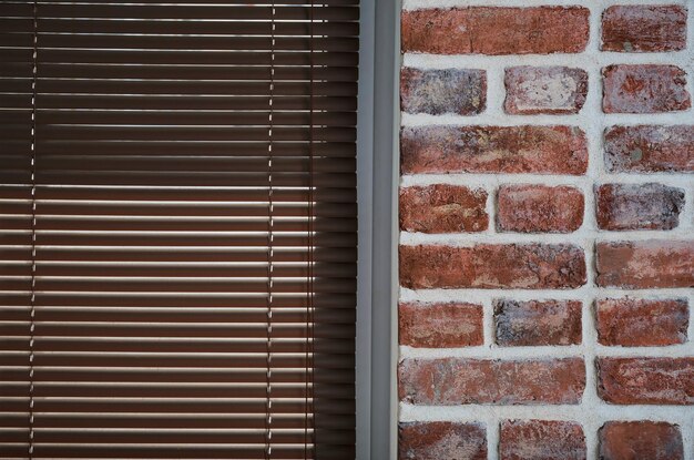 Window with brown blinds and a brick wall made of old bricks loft interior industrial interior as a background closeup