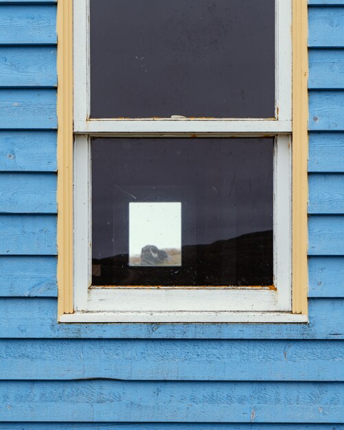 window on a wooden blue wall of a cottage