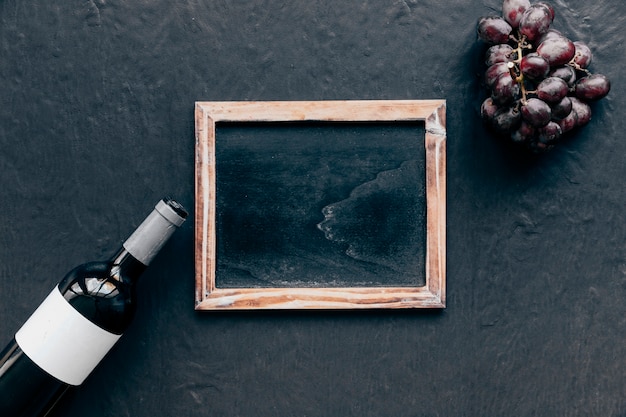 Free photo wine bottle and grape near chalkboard