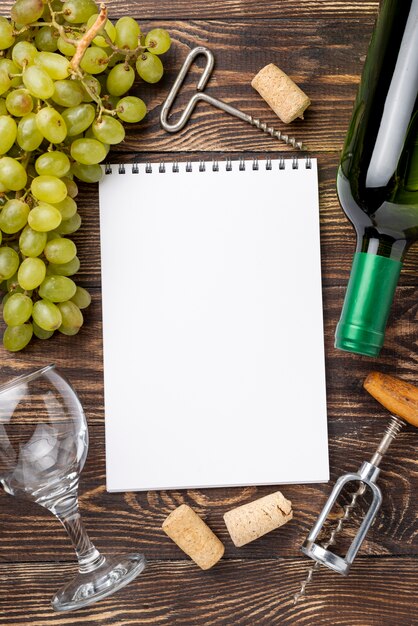 ワインのボトルとノートの横にあるブドウ