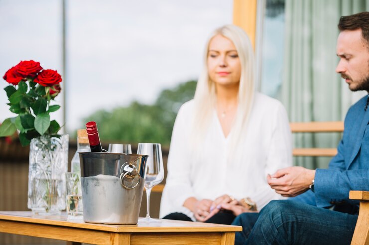 Free Photo wine bottle inside the ice bucket in front of couple sitting together
