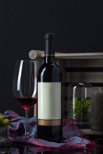 Wine bottle with goblet, plant, scarf, candle and wooden box