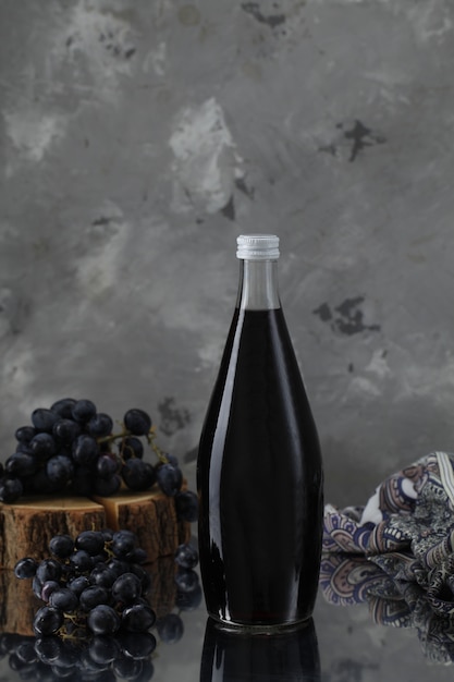 Free photo wine bottle with grapes on wooden piece