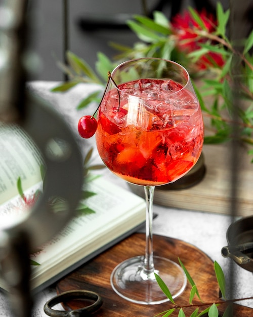 A wine glass with cherry cocktail garnished with cherry