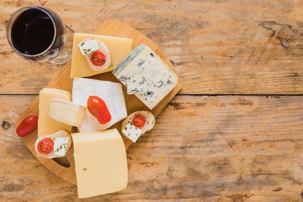 Wine glasses with grapes and variety of cheese blocks on wooden desk