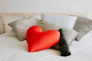 Free photo wine and heart cushion on bed