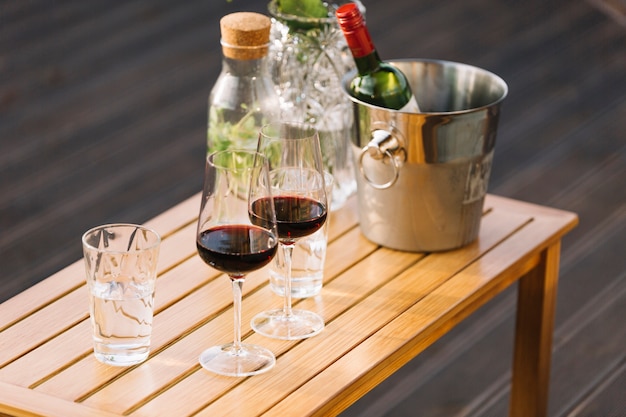 Wineglasses and ice bucket with wine bottle on small wooden table