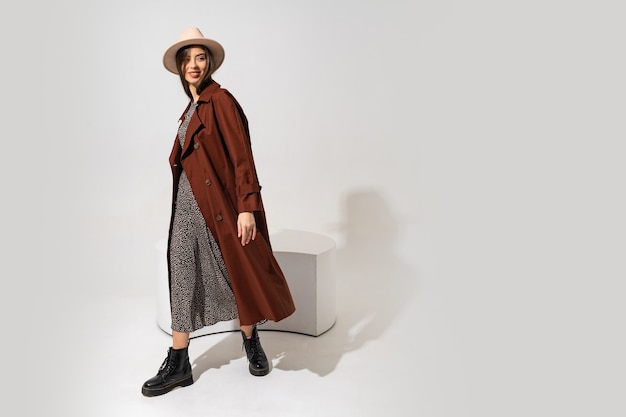 Winer fashion look. Stylish brunette model in brown coat  and beige hat posing