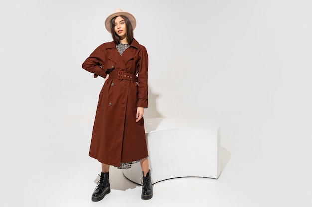 Winer fashion look. Stylish brunette model in brown coat  and beige hat posing