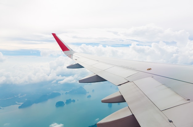 Wing of an airplane flying above sea and island