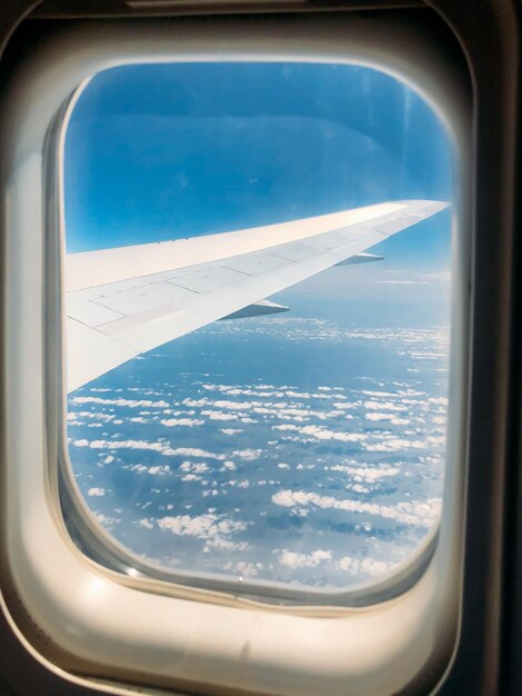 Крыло через окно самолета в удивительном небе на закате