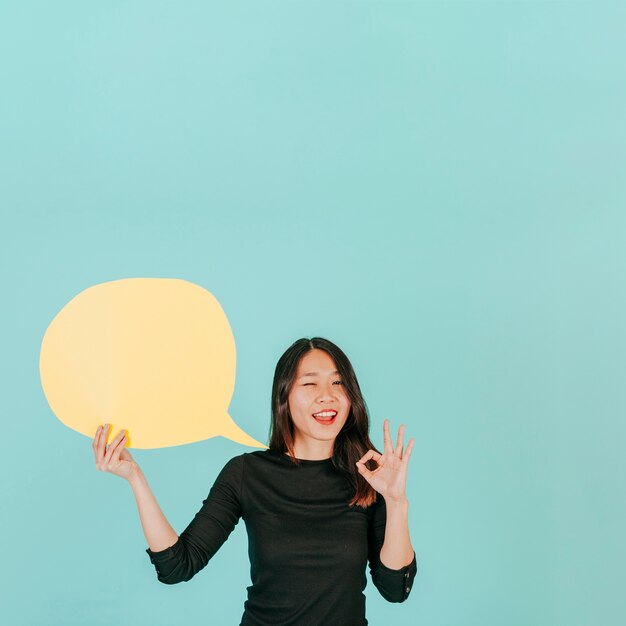 Winking woman with speech bubble gesturing OK